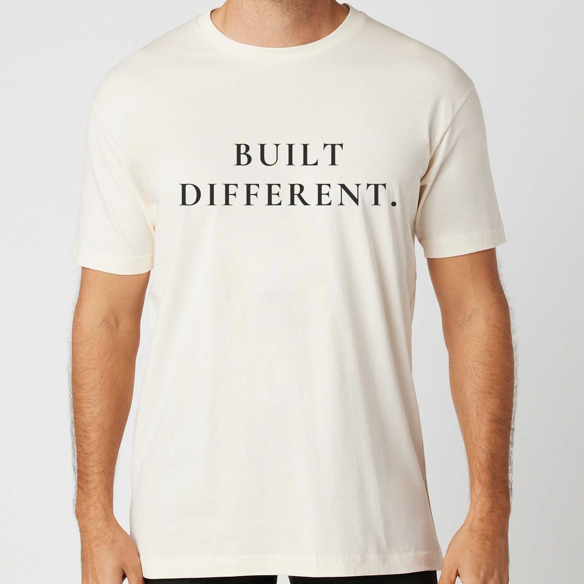 Person wearing a vintage white t-shirt with 'BUILT DIFFERENT.' text on a plain background